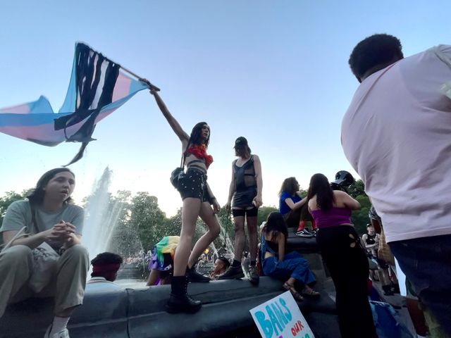 Women flying a flag atop a fountain
